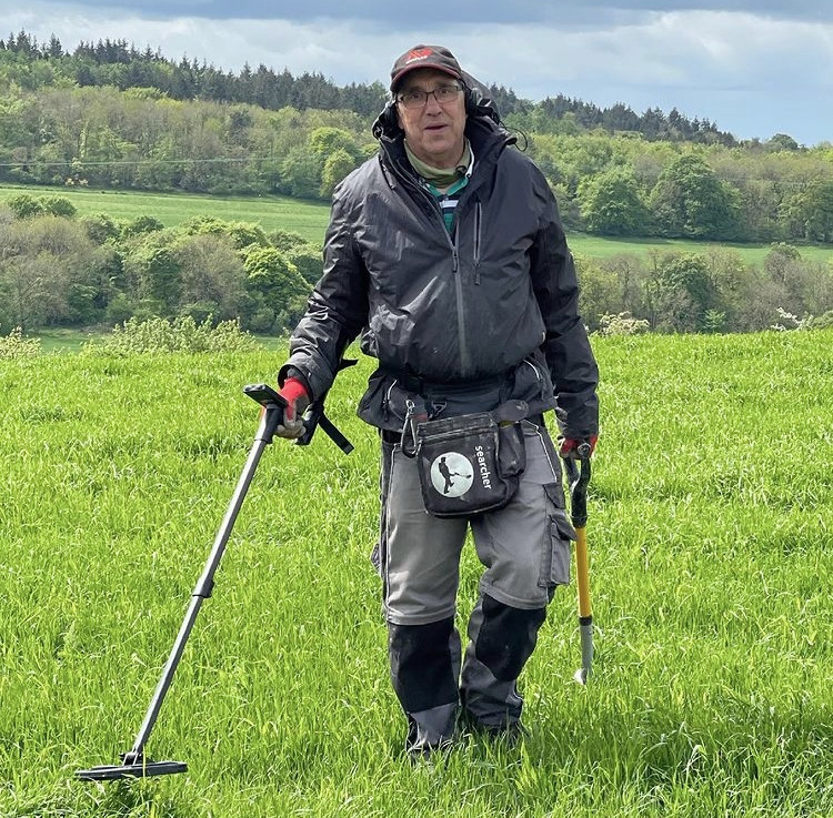 man in a uk field using an XP Deus metal detector